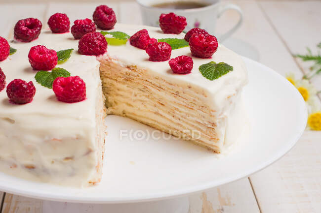 Tasty healthy keto crepe cake with erythritol sweetener decorated with ripe raspberries served on wooden table with decorative twigs in kitchen — Stock Photo