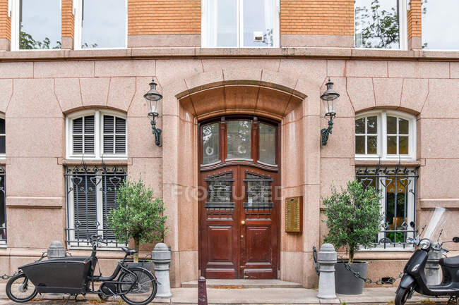 Maison vieillie extérieure contre la chaussée et vélos garés entre les arbres envahis dans la journée à Amsterdam Hollande — Photo de stock