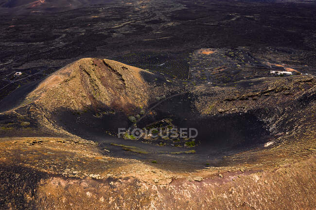 Vue paysage du vignoble dans le cratère du volcan contre les monts secs sous un ciel clair à Geria Lanzarote Îles Canaries Espagne — Photo de stock
