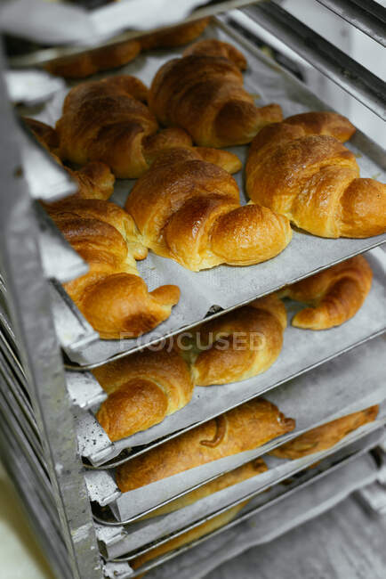 De cima de croissants caseiros aromáticos saborosos colocados na bandeja de cozedura na padaria — Fotografia de Stock