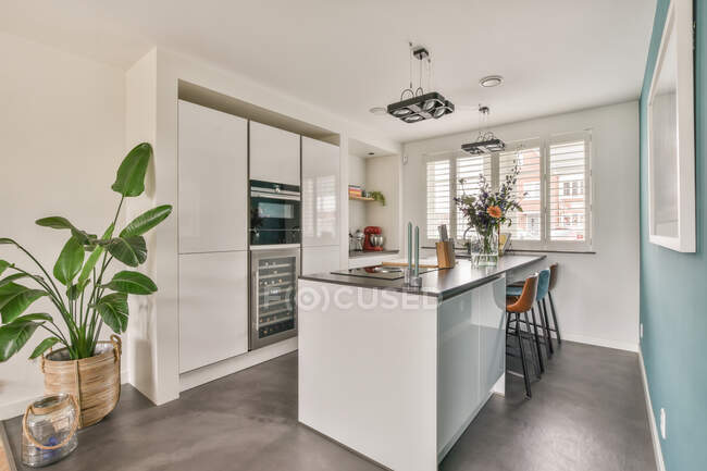Interior da cozinha contemporânea com mobiliário de estilo minimalista e sala de jantar em apartamento iluminado pelo sol — Fotografia de Stock
