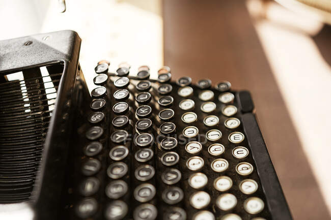 D'en haut de la vieille machine à écrire noire vintage avec des boutons colorés placés sur la table à la lumière du soleil — Photo de stock