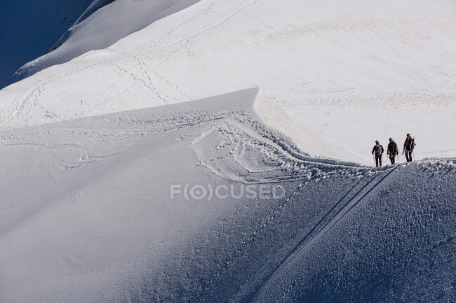Vista da Aiguille du Midi Chamonix punto di vista di viaggiatori senza volto in vestiti caldi e zaini a piedi sul pendio innevato della montagna del Monte Bianco in giornata invernale nella natura — Foto stock