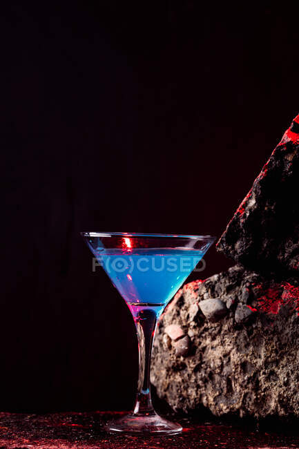 Cocktail Blue Lagoon in cristallo elegante disposto su superficie ruvida su fondo nero — Foto stock
