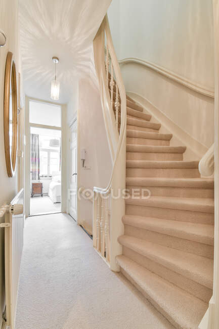 Stairway in narrow corridor with lamp and mirror leading to bedroom on sunny day in cozy apartment — Stock Photo