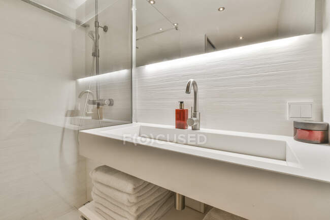 Interior do banheiro contemporâneo com lavatório e espelho contra chuveiro com parede de vidro em casa de luz — Fotografia de Stock