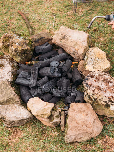 Desde arriba de la quema de carbón y la antorcha con chispas de naranja rodeada de piedras en bruto en el camping - foto de stock