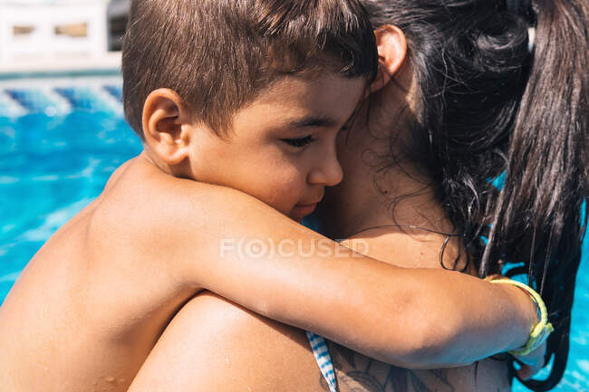 Vue latérale d'une mère méconnaissable avec un fils fatigué debout en nageant le jour ensoleillé d'été — Photo de stock
