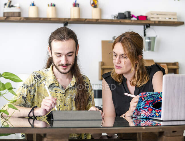 Designers criativos masculinos e femininos desenhando esboços em tablets gráficos enquanto trabalham juntos no projeto no espaço de trabalho — Fotografia de Stock