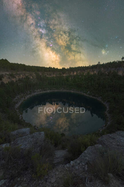 Picturesque view of lagoon reflecting trees growing on mounts under starry sky in Cuenca Spain — Stock Photo