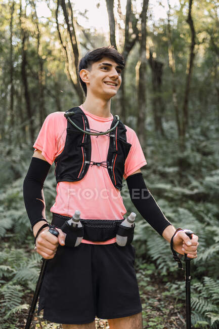 Man traveler with trekking poles walking up in jungle — Stock Photo