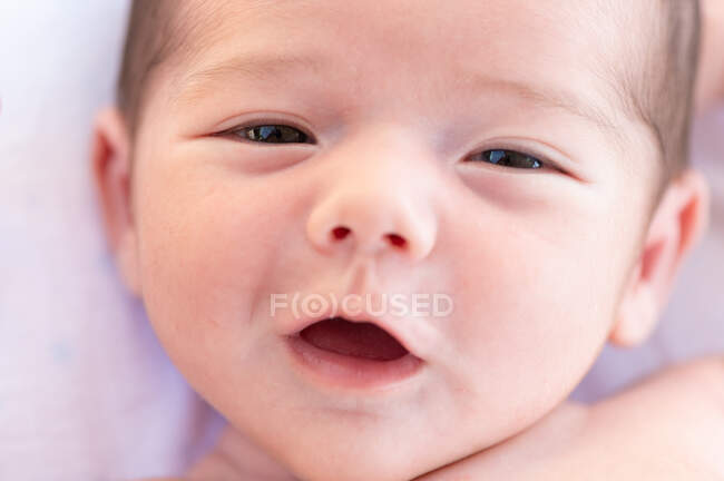 From above adorable naked in infant sweetly lying on soft bed at home — Stock Photo