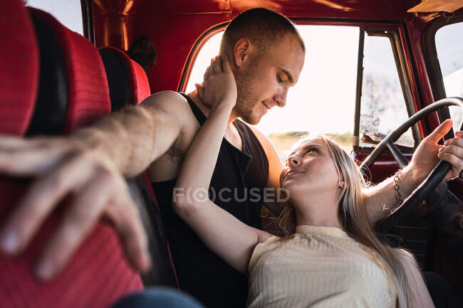 Casal amoroso olhando um para o outro no carro vintage estacionado na natureza no dia ensolarado — Fotografia de Stock