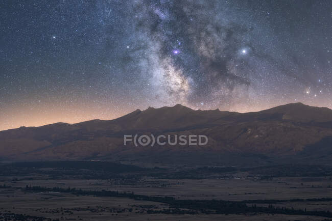 Вид зоряного неба з галактикою та міжзоряним газом над величними кряжами під час заходу сонця. — стокове фото
