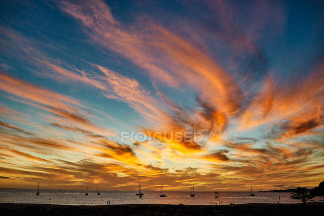 Abendhimmel mit leuchtend orangen Wolken über dem Meerwasser mit Booten auf Fuerteventura, Spanien — Stockfoto
