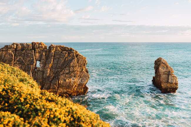 Вражаючі краєвиди нерівного скелястого берега, обмитого пінистими морськими хвилями під блакитним хмарним небом у Лієнкрес - Кантабрії (Іспанія). — стокове фото