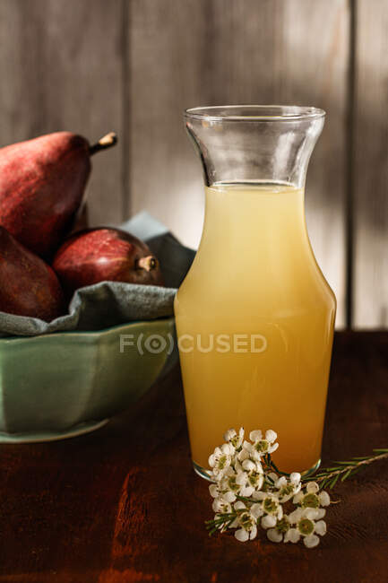 Jar of delicious refreshing drink with pear juice and fresh elderflower leaves on table — Stock Photo