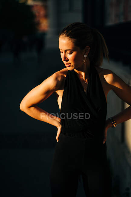 Feminino vestindo roupas da moda em pé na cidade no dia ensolarado e olhando para longe — Fotografia de Stock