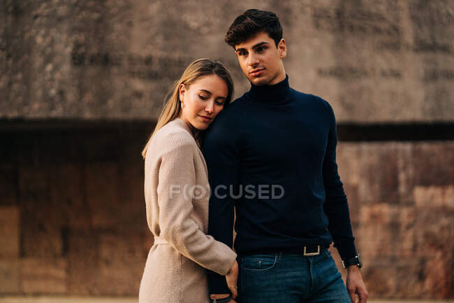 Jovem casal elegante de pé perto uns dos outros na rua da cidade e olhando para longe — Fotografia de Stock