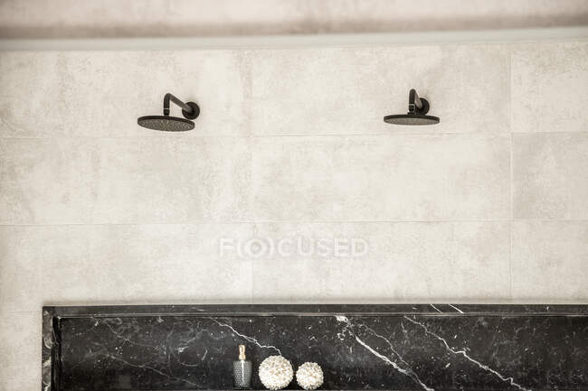 Interior del baño con cabina de ducha con manijas de grifo negro y manguera en paredes blancas - foto de stock