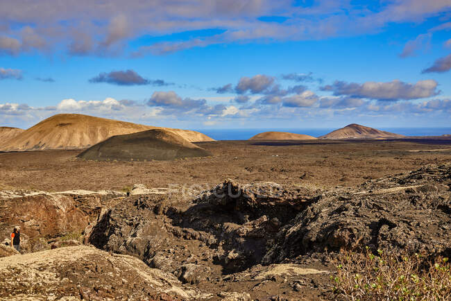 Vue grand angle de collines rocheuses sèches situées dans les hautes terres contre un ciel nuageux en été à Fuerteventura, Espagne — Photo de stock