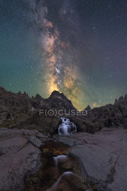 Spektakulärer Blick auf hohe raue Berge mit Kaskade und Fluss unter Sternenhimmel mit Galaxie am Abend — Stockfoto