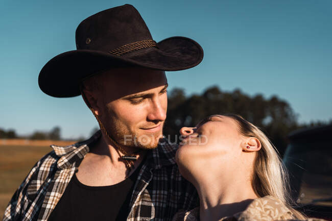 Jovem casal apaixonado pelo pôr do sol enquanto olham um para o outro no verão — Fotografia de Stock