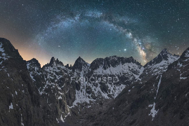 Espectacular vista de la galaxia en el cielo con gas interestelar sobre el monte majestuoso áspero con nieve en la noche - foto de stock