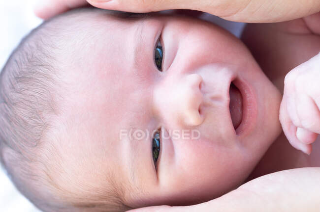 Primo piano del raccolto madre anonima toccare la testa del bambino carino sorridente e guardando la fotocamera — Foto stock
