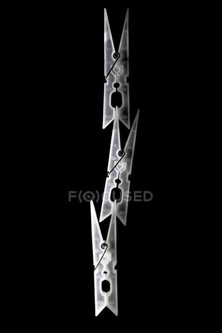 Roupas pegs ligados para formar uma torre sobre fundo preto — Fotografia de Stock