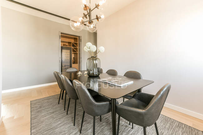 Interior da sala de jantar com mesa preta e cadeiras em apartamento contemporâneo projetado em estilo mínimo — Fotografia de Stock