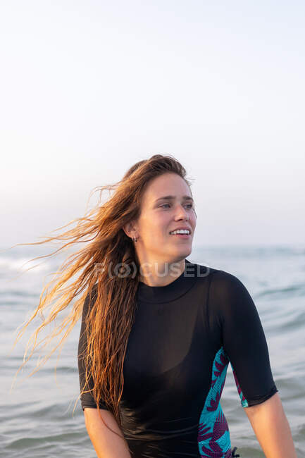 Delighted female surfer lying on SUP board and floating on calm water of sea on sunny day — Stock Photo