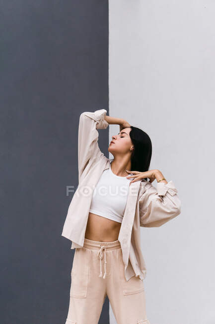 Creative female dancer in white clothes dancing in city street during performance touching head with hand — Stock Photo