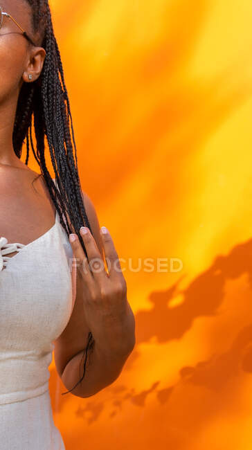 Неузнаваемая афроамериканка бросает длинные плетеные волосы на ярко-желтом фоне в Барселоне — стоковое фото