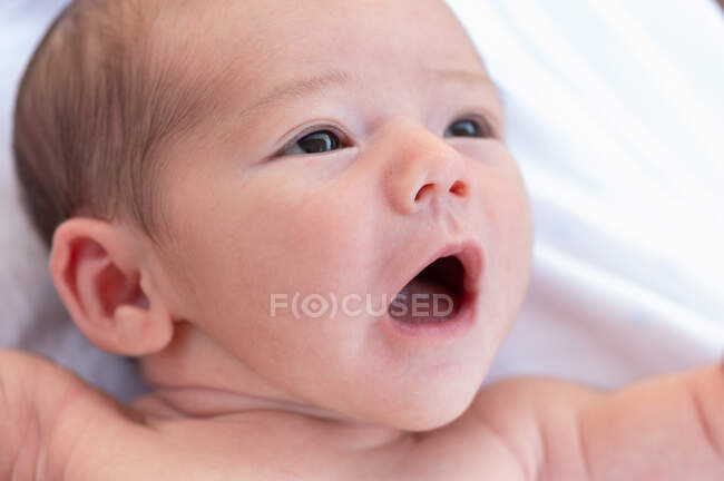 Desde arriba adorable desnudo en el niño bostezando dulcemente mientras está acostado en la cama suave en casa - foto de stock