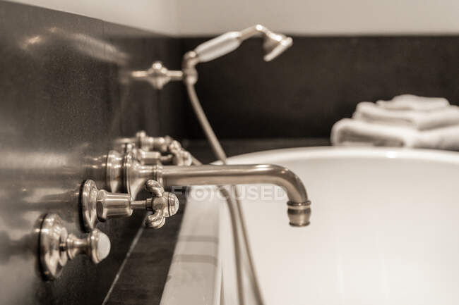 Focus sélectif sur le robinet chromé installé sur la baignoire avec buse de douche dans la salle de bain moderne — Photo de stock