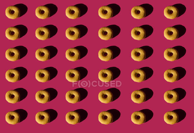 Vista superior del fondo de rosquillas clásicas sin cubierta sobre fondo rosa - foto de stock