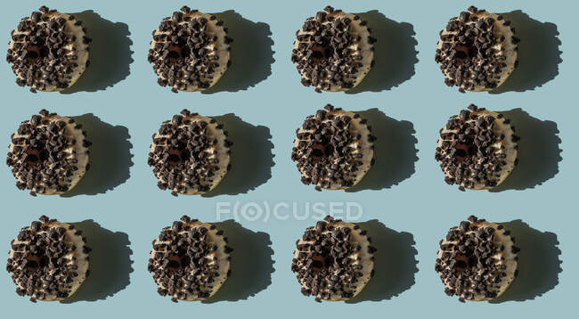 Vista superior de muchas rosquillas blancas cubiertas con trozos de bizcocho oreo sobre fondo azul - foto de stock