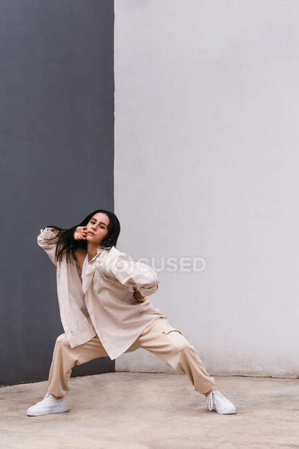 Talentuosa ballerina che si muove e balla vicino al muro di cemento nell'area urbana della città guardando la macchina fotografica — Foto stock
