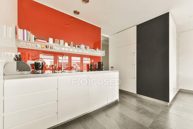 Kücheninsel mit Theke und Barhockern unter der Haube in moderner Freiraumwohnung mit weißen Wänden mit Möbeln und Utensilien — Stockfoto