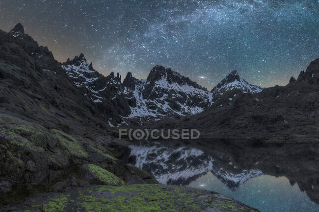 Vista pitoresca do céu estrelado com galáxia refletindo em lago contra monte com neve ao entardecer — Fotografia de Stock