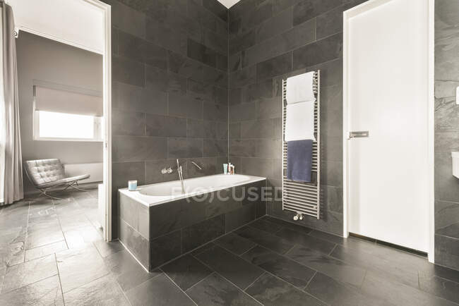 Интерьер просторной ванной комнаты с серой плиткой стены и пол и белая ванна и раковины — стоковое фото
