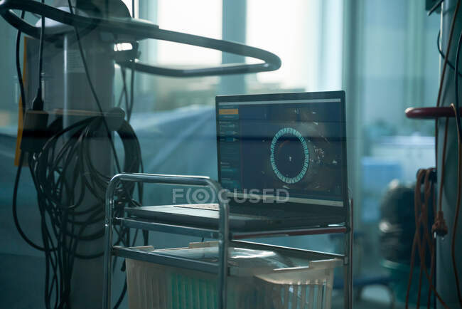A través de la vista de la pared de cristal de netbook con fotografía de ojo humano en la pantalla en el quirófano - foto de stock