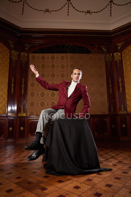 Full body of elegant classy male theater performer in suit gesticulating with arms raised during emotional speech in retro style studio — Stock Photo
