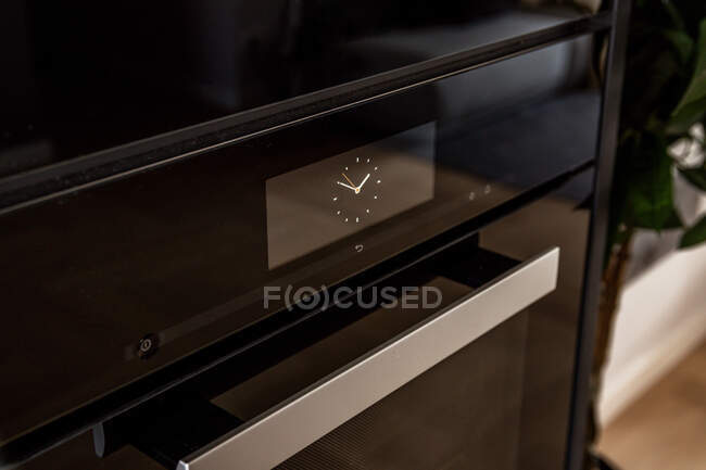 Панель керування з таймером на чорній сучасній пічці, розміщеній на кухні в квартирі — стокове фото