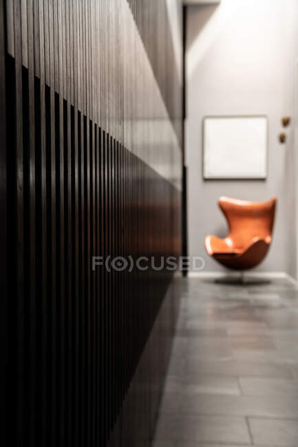 Vue en perspective de l'intérieur du couloir avec des murs gris rayés et une chaise brune placée près de la porte d'entrée — Photo de stock