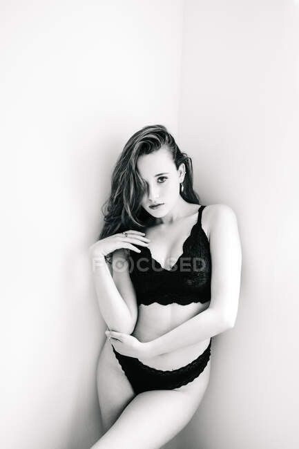 Black and white sexy female in underwear standing in corner of room and looking at camera — Stock Photo