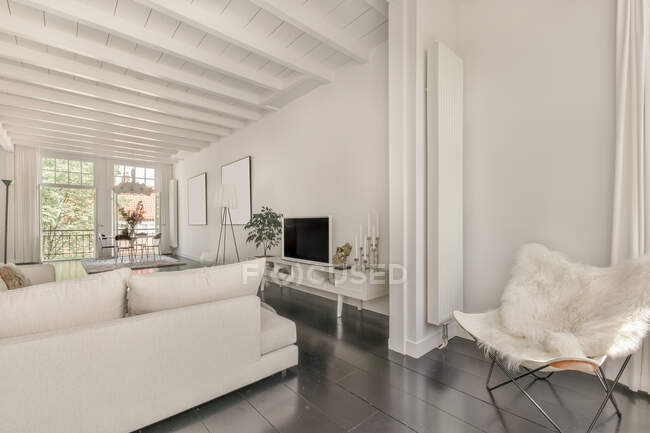 Просторная белая гостиная с удобным диваном и стулом в современном доме — стоковое фото
