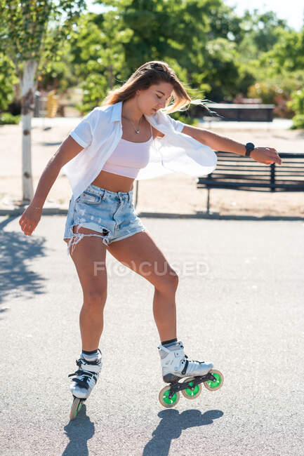Giovane in forma femminile in pattini mostrando acrobazia su strada in città in estate — Foto stock