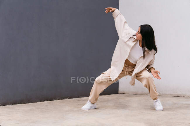 Talented female dancer moving and dancing near concrete wall in urban area in city — Stock Photo